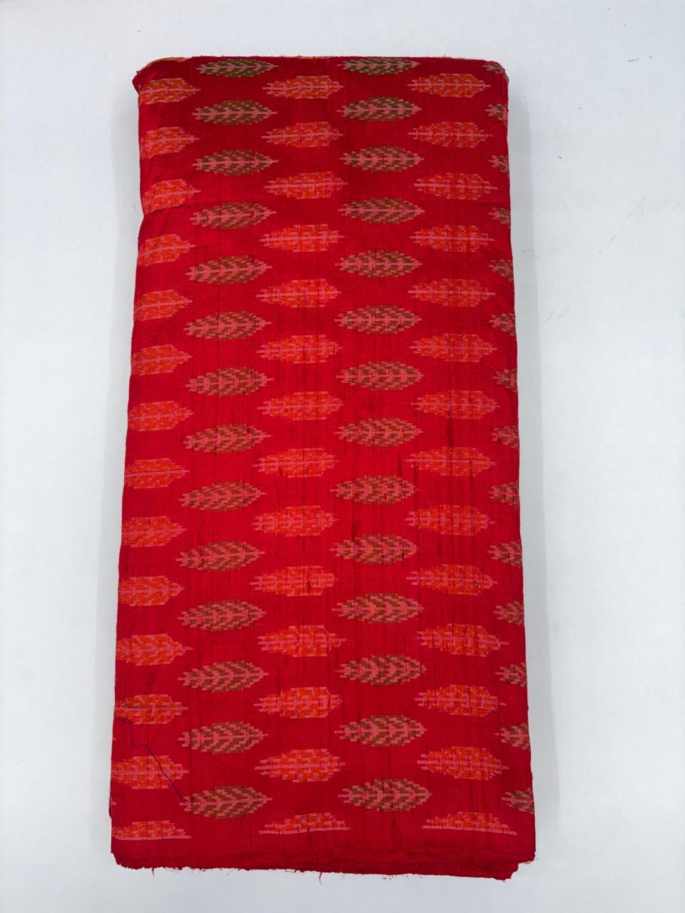 Folded bolt of vibrant red pure raw silk fabric featuring alternating leaf and chevron Ikat motifs with Silk Mark quality weave