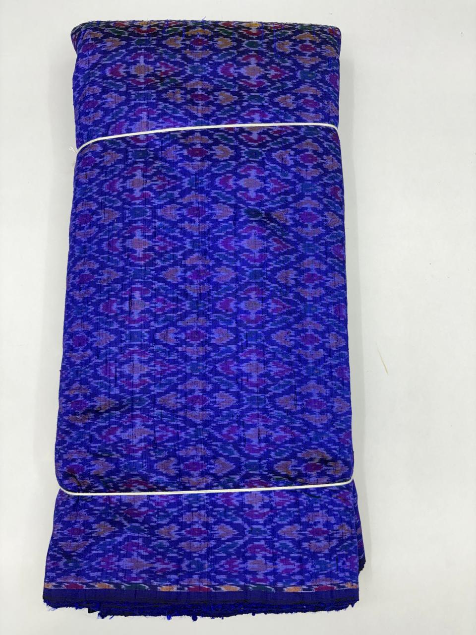 Folded bolt of royal blue pure raw silk fabric featuring an intricate purple and violet diamond Ikat weave with Silk Mark authenticity