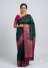 Woman draped in a bottle green pure Kanchi soft silk saree featuring a rich magenta pink zari woven border and matching blouse, Silk Mark certified