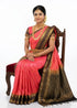 Woman wearing a pure Kanchipuram pattu saree featuring a pink silk body with gold zari motifs.
