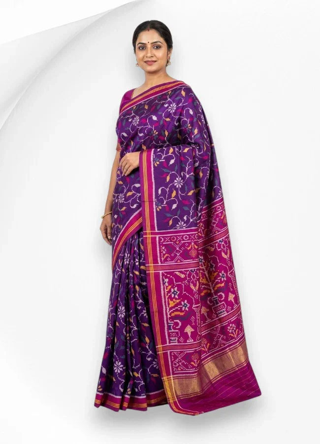 A beautifully draped deep purple pure Patola silk saree showcasing traditional white and yellow floral Ikat motifs on the body, contrasted with a rich magenta pallu featuring classic vase and geometric patterns.