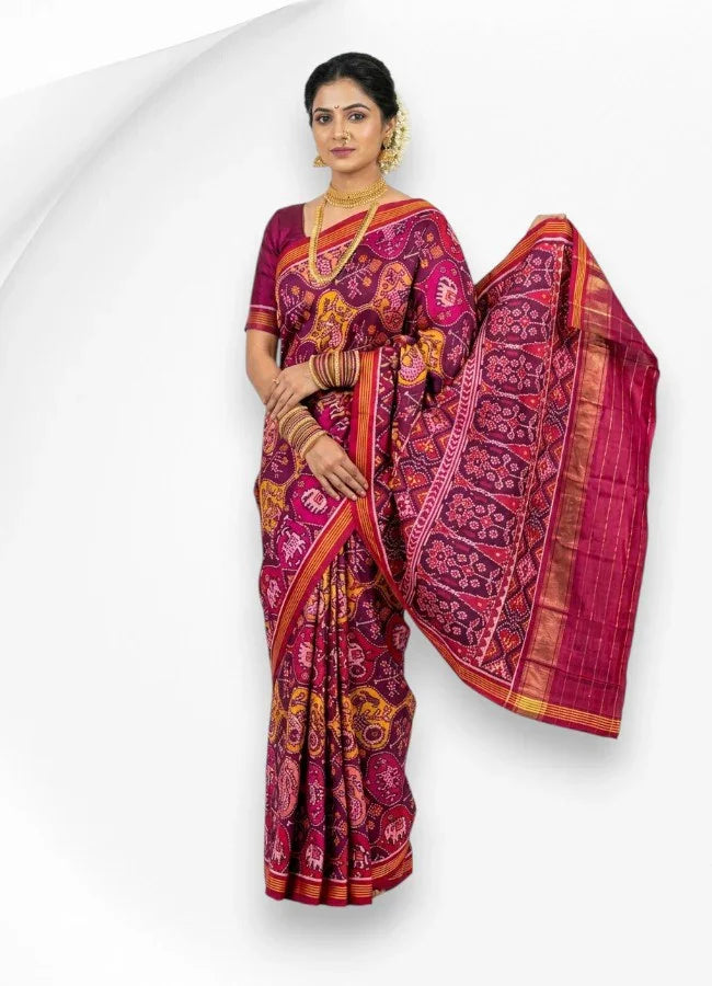 A woman wearing a beautiful pure real Patola silk saree in magenta and purple, showcasing an intricate traditional elephant and floral woven pallu.