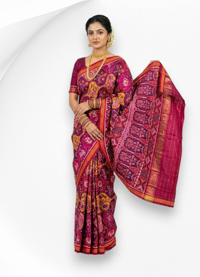 A woman wearing a beautiful pure real Patola silk saree in magenta and purple, showcasing an intricate traditional elephant and floral woven pallu.