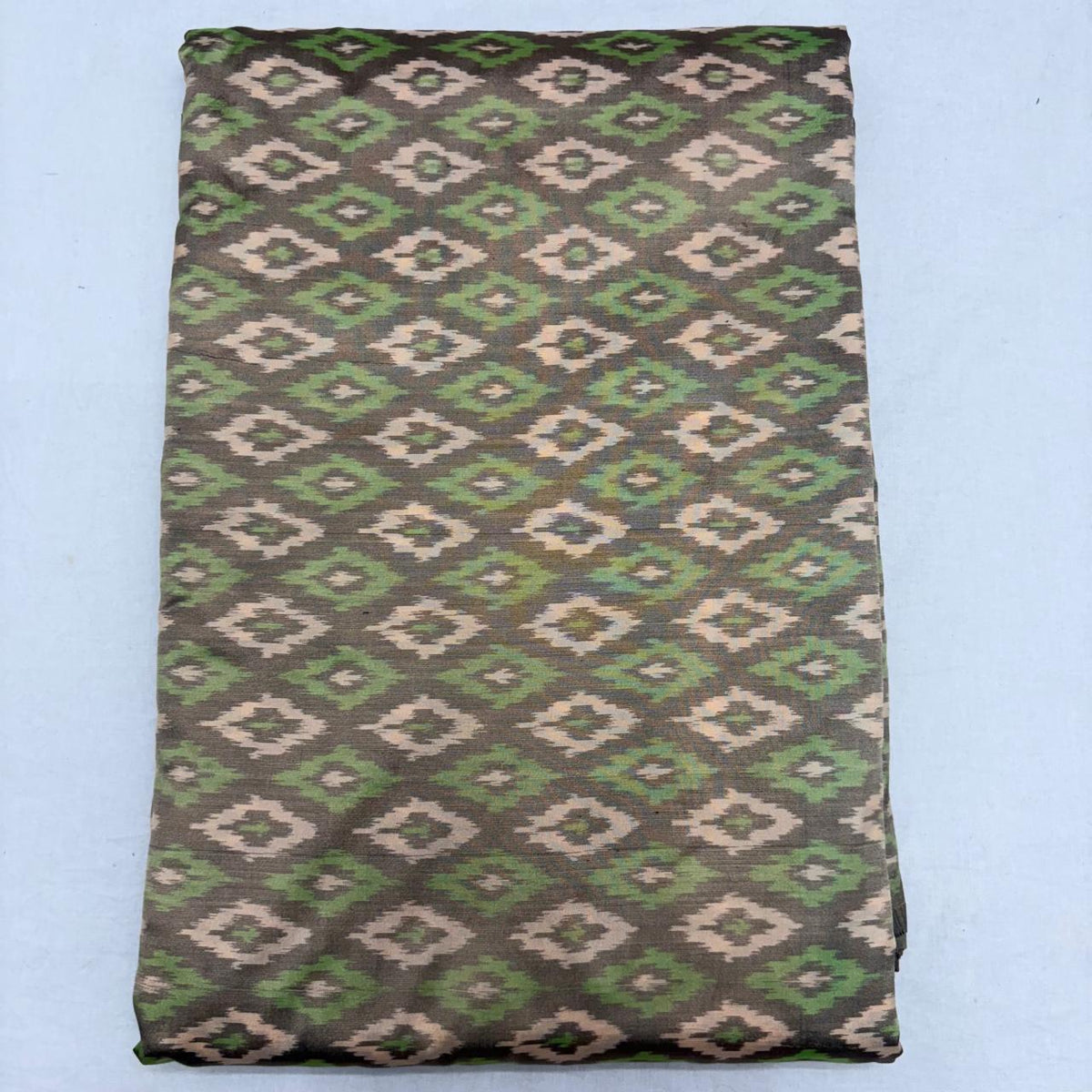 Folded charcoal grey pure silk Ikat fabric featuring alternating olive green and beige geometric diamond motifs with Silk Mark certification