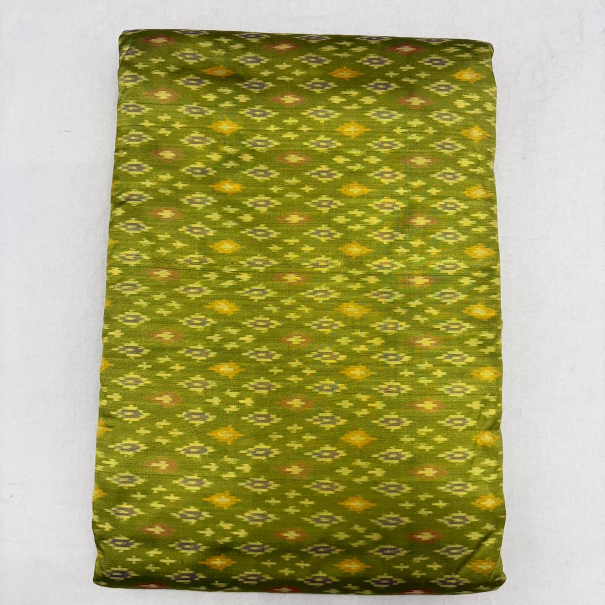 Folded olive green pure silk Ikat fabric featuring geometric golden yellow and rust diamond motifs with Silk Mark certification