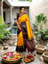 Model wearing a yellow soft silk saree with a dark chocolate brown floral zari border and matching chocolate brown blouse