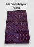 Folded dark purple Sambalpuri Ikat cotton fabric featuring traditional horizontal woven motifs in lavender and orange, displayed on a wooden surface next to artisan wooden blocks.