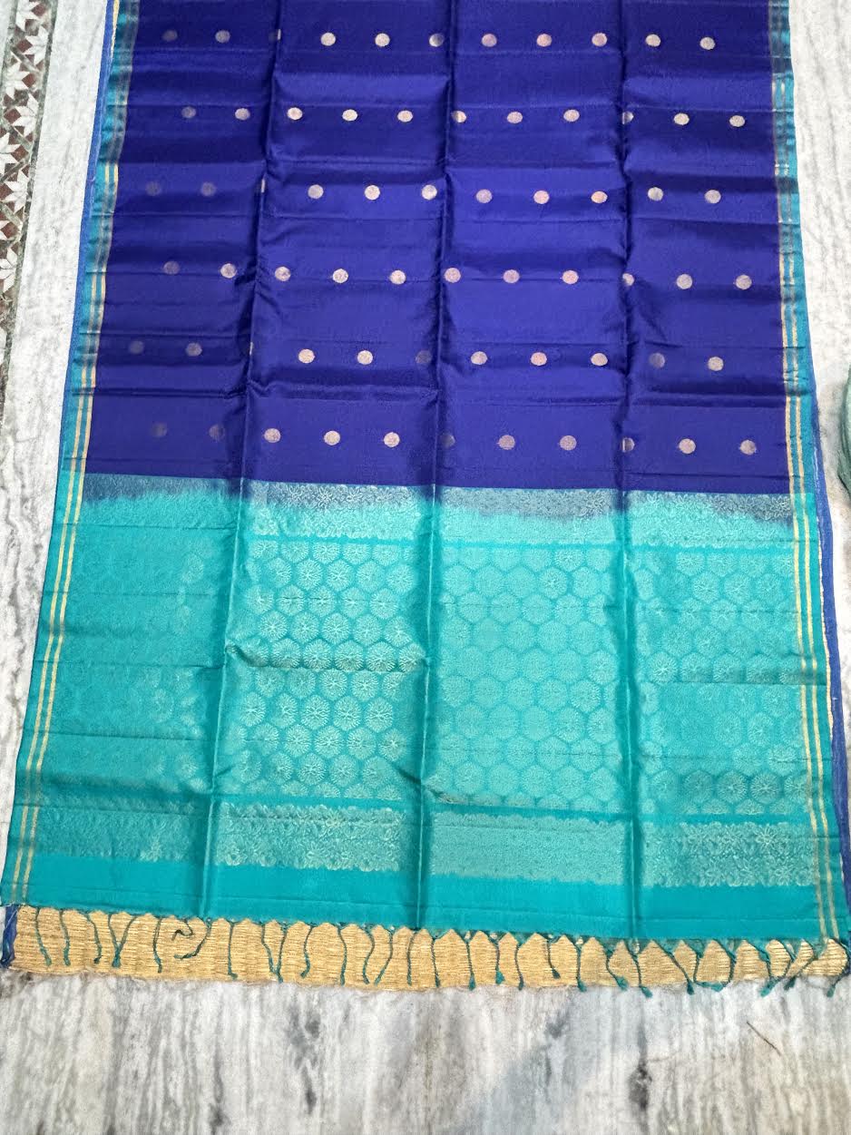 Royal blue Kanchipuram soft silk saree with gold zari buttas and an ornate teal contrast pallu with tassels
