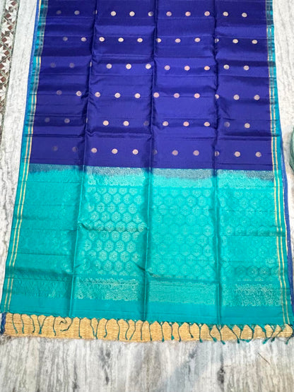 Royal blue Kanchipuram soft silk saree with gold zari buttas and an ornate teal contrast pallu with tassels