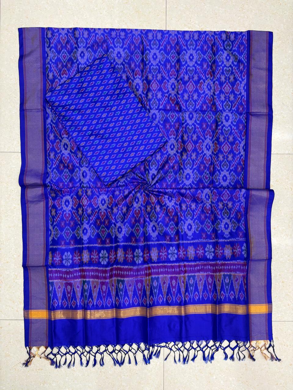 Royal blue Pochampally Ikat silk unstitched dress material set featuring intricate handwoven geometric motifs, a detailed temple pattern border with gold stripes, and matching blue tassels.