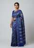 Indian woman draped in an elegant royal blue pure silk Patola saree featuring traditional animal motifs, standing against a clean neutral studio backdrop.