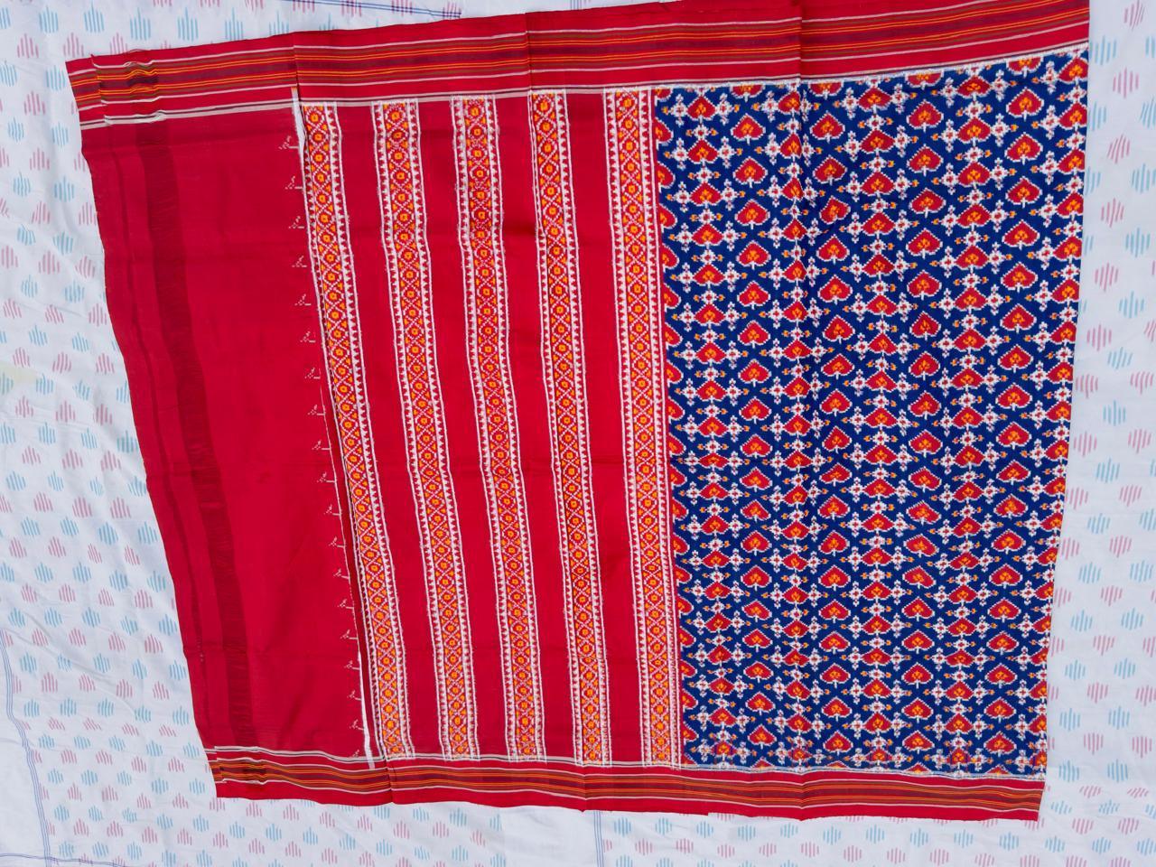 Flat lay of an authentic double ikat patola silk saree with a royal blue geometric patterned body, red striped pallu, and Silk Mark certification