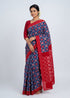Indian woman draped in royal blue and crimson red double ikkat handloom cotton saree on neutral background