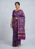 Model wearing a royal purple traditional Patola silk saree with elephant motifs and a plain purple blouse against a light studio backdrop.