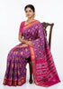 A beautiful traditional Indian woman sitting elegantly on a dark wood chair, wearing a royal purple and pink Ikkat silk Patola saree with geometric patterns and a gold zari border, set against a seamless white background.