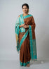 Woman posing in a traditional rust brown silk saree with turquoise zari border and pallu tassels