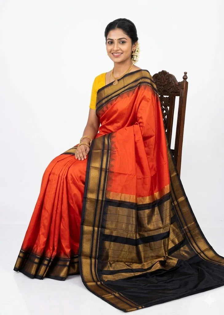 An ultra-realistic high-resolution photograph of a smiling traditional Indian woman seated on an antique carved wooden chair against a pure white backdrop. She is draped in a vibrant Sindoori red pure Gadwal silk saree featuring an elaborate black and gold zari temple border and a complex striped black and gold zari pallu, complemented by a mustard yellow blouse and jasmine flowers in her hair.