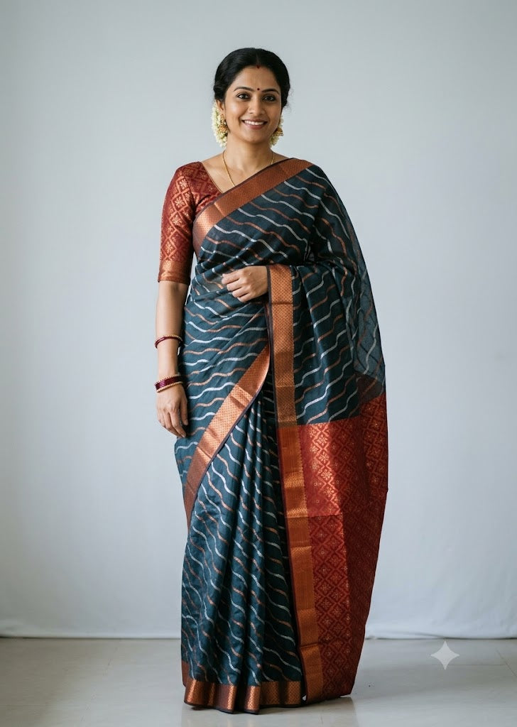 Woman wearing a traditional deep teal blue Kuppadam Pattu saree with wavy silver and copper zari stripes, copper zari border, and contrast maroon red floral brocade pallu and blouse.