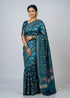 Woman wearing a teal blue Patola silk saree with golden jewelry and traditional bird motifs - front view